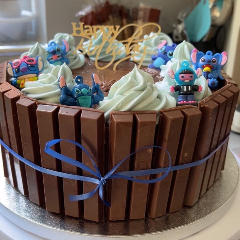 KitKat celebration cake with character toppers and a blue ribbon